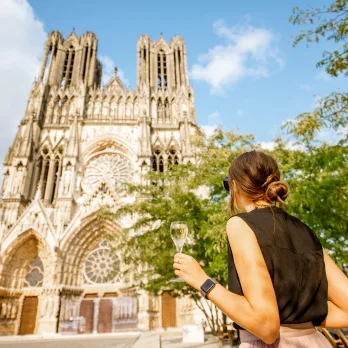 touriste devant cathedrale de Reims en buvant une coupe de champagne
